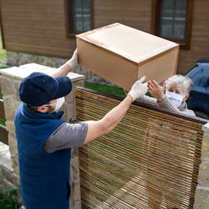 a man hands a package over a gate to an elderly woman