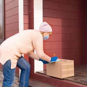 a woman leaves a package on a porch