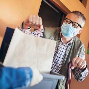 an elderly man with a cane receives a meal delivery